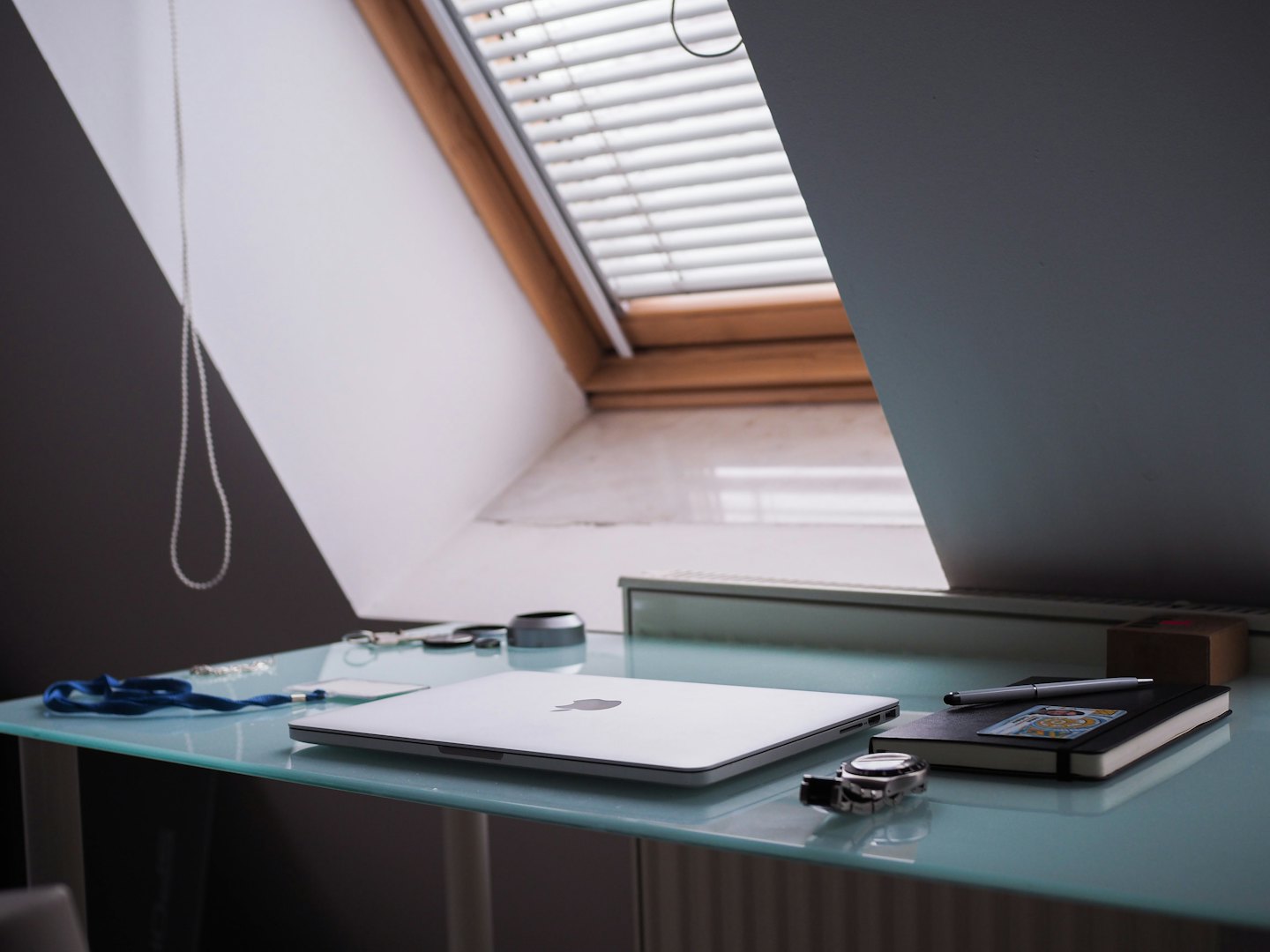 Moderne thuiskantoor met laptop, notitieboekje en pen op glazen bureau.